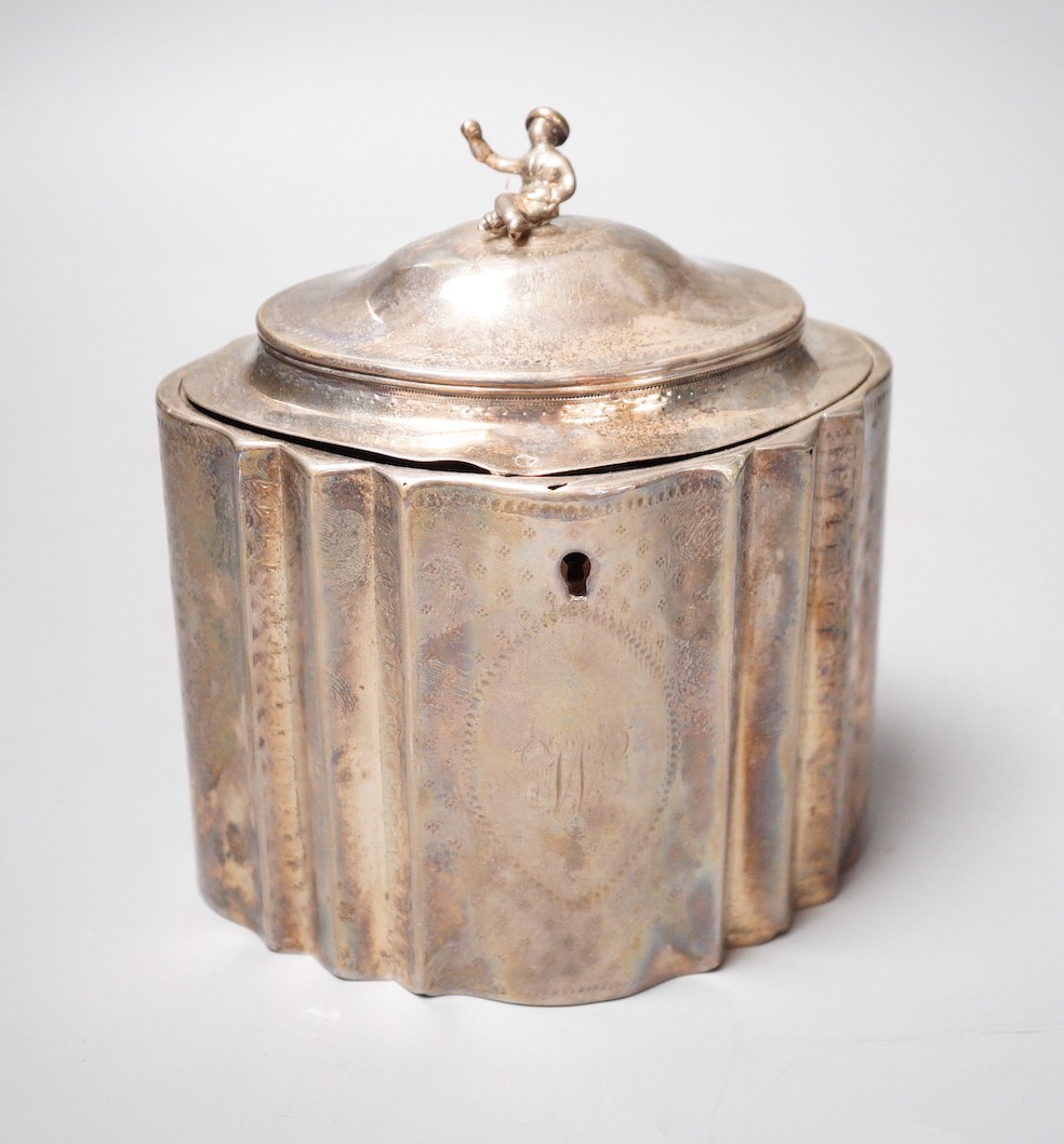 A George III engraved silver shaped oval tea caddy, the finial modelled as a seated oriental figure, Robert Hennell I, London, 1789, height 15cm, 12.5oz (a.f.), no key.